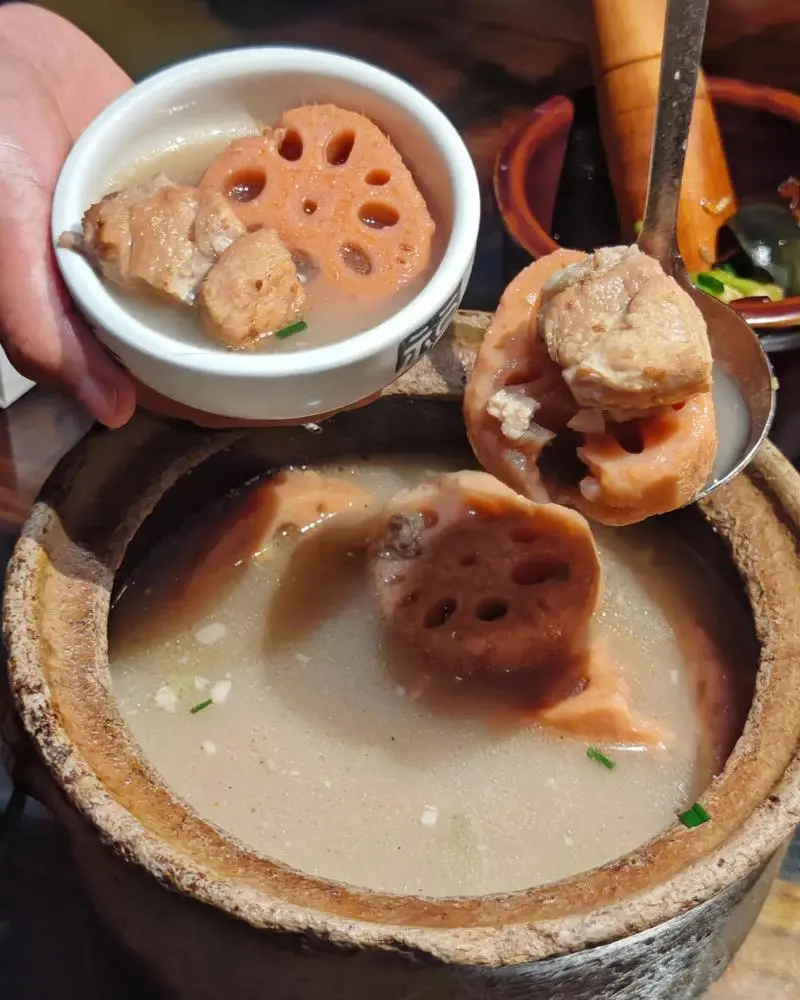 Family eating lotus root and pork rib soup together at home in winter, bowls steaming