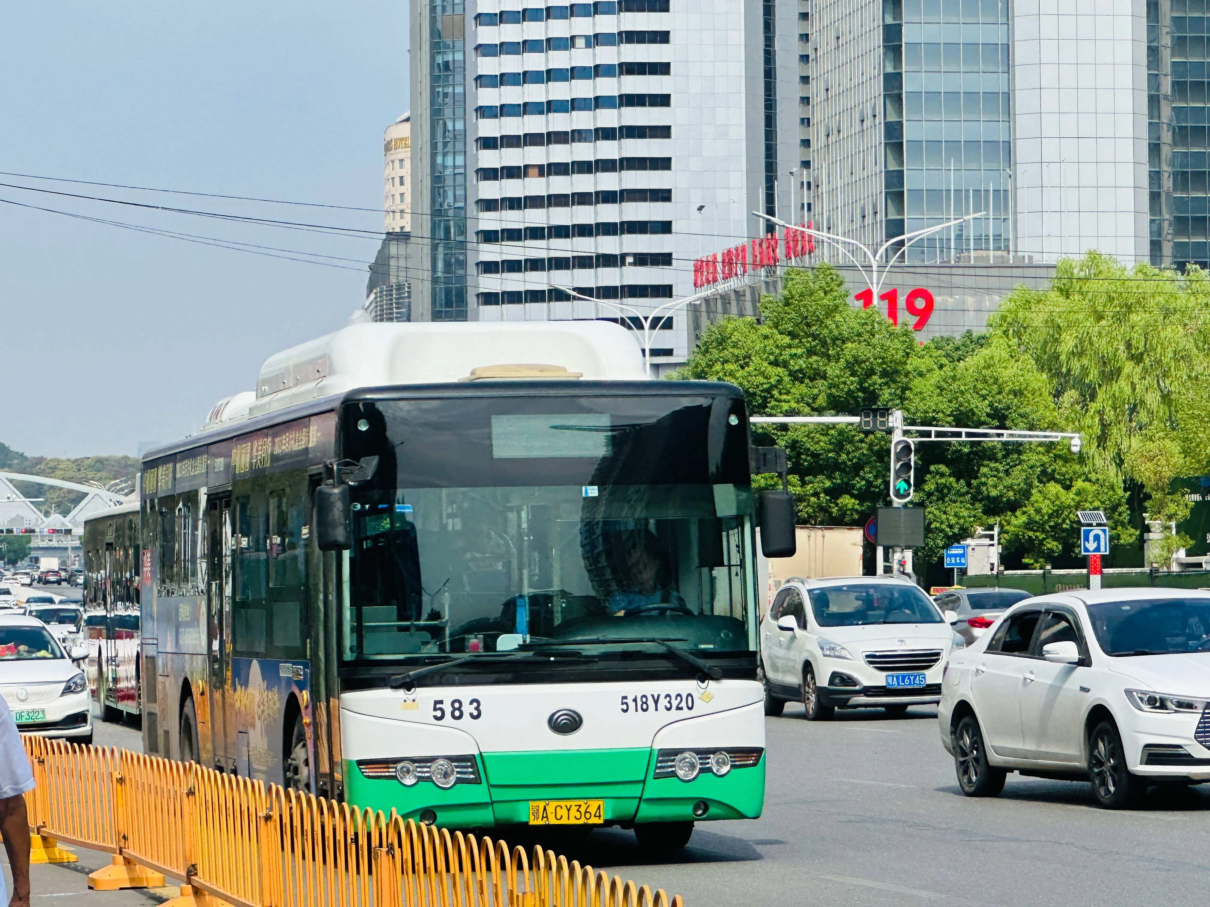 A Wuhan city bus navigating through traffic on a busy boulevard, leaning slightly into a turn, with buildings and pedestrians blurring past