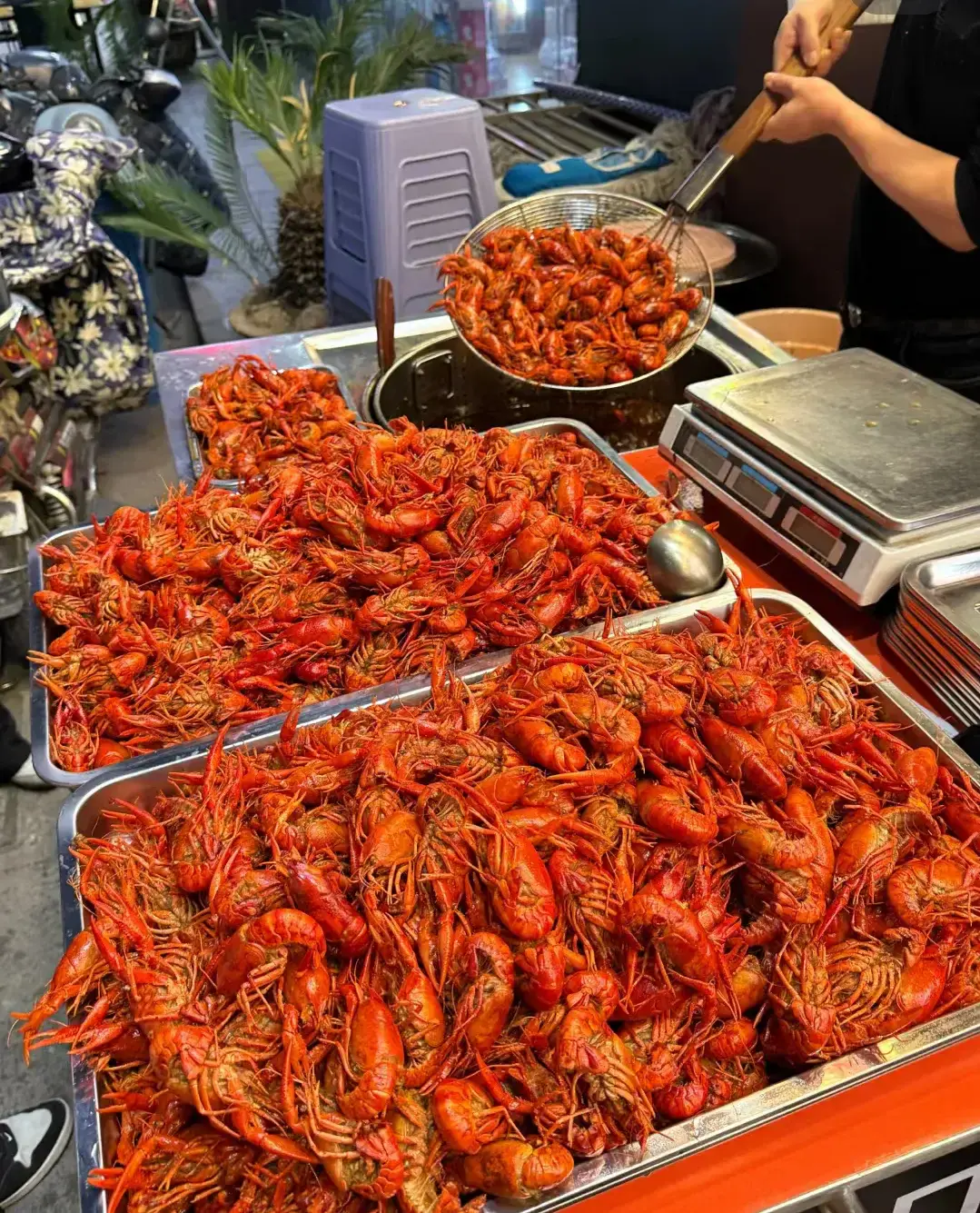 Roadside crayfish stall in Wuhan with wok steaming, owner stir-frying crayfish, folding tables full of diners