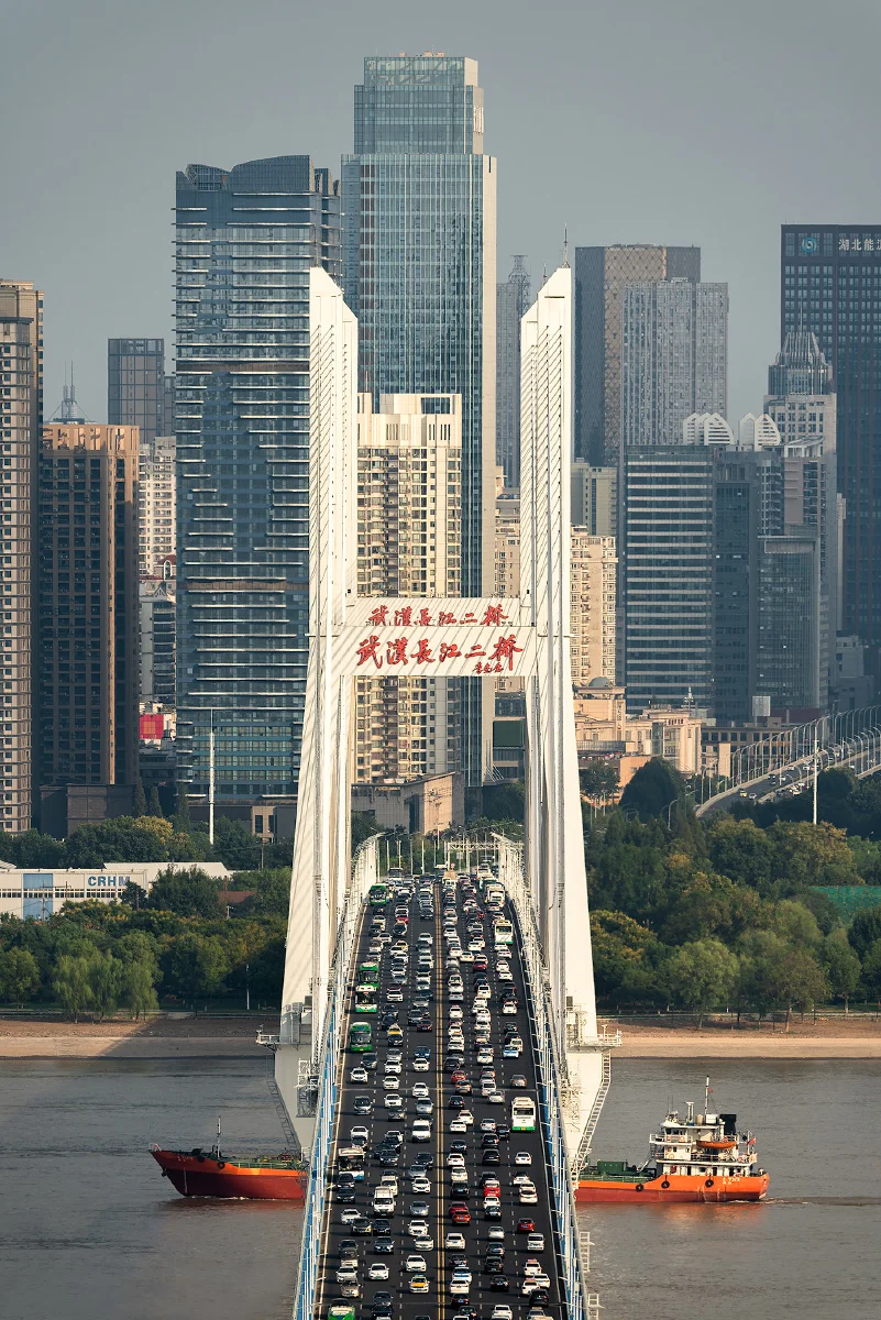 Morning rush hour traffic on the Yangtze Bridge in Wuhan, with streams of vehicles crossing the river as the sun rises