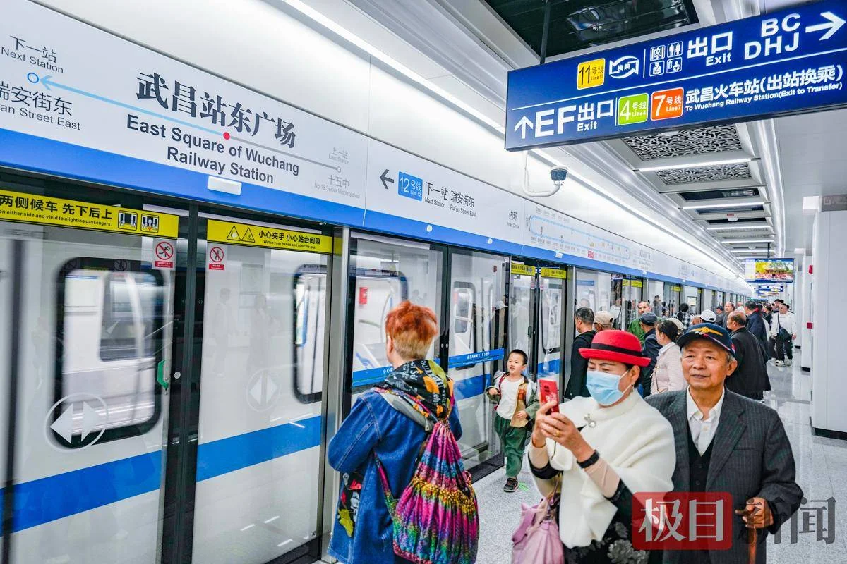 Wuhan commuters walking briskly through a metro station transfer corridor during rush hour, showing the daily flow of city workers