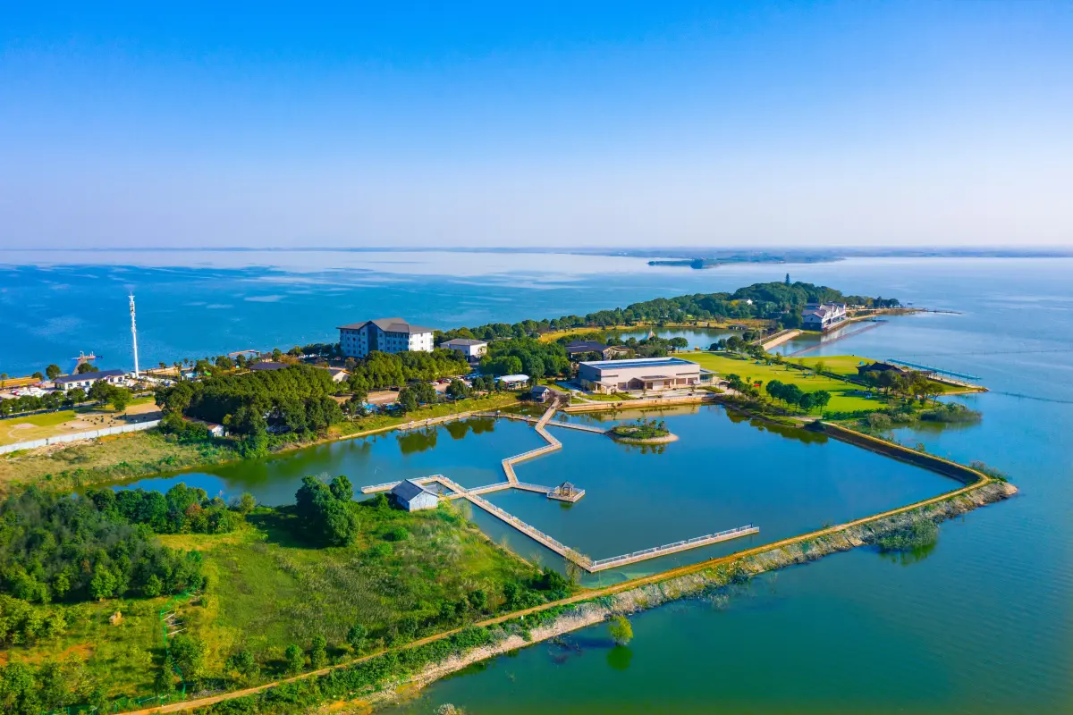 Liangzi Lake in autumn southeast of Wuhan, calm water with fishing boats and distant island silhouette