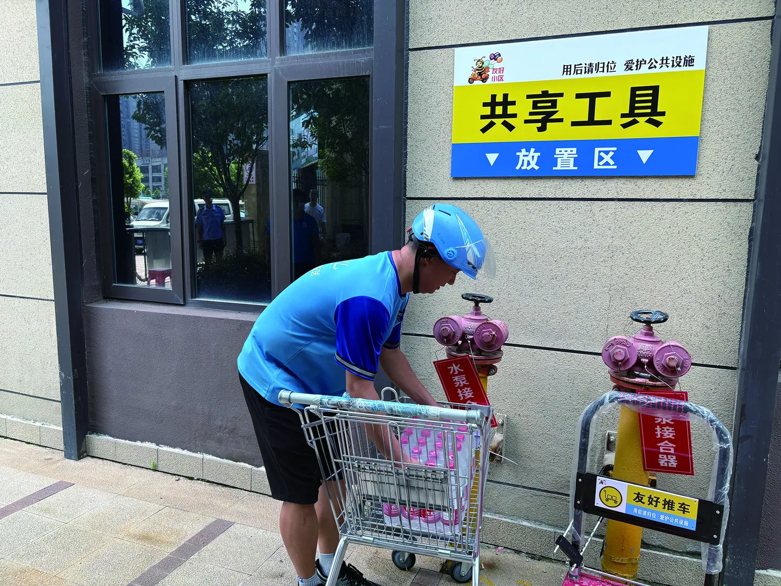 Delivery rider in helmet at a residential compound gate at night, exchanging words with a gate guard under dim light