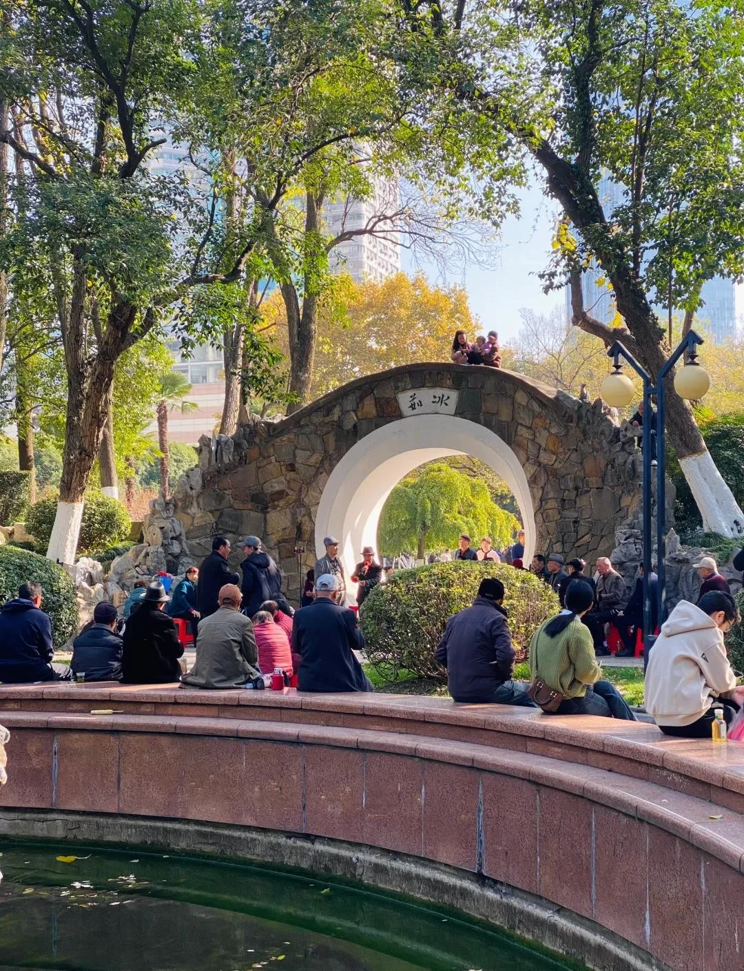 Older Wuhan locals socializing in a park or by a riverside, showing how deep community bonds translate into the city's distinctive way of addressing each other