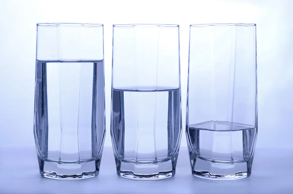 Three small baijiu glasses showing different fill levels — full, three-sip, and a small sip — arranged on a table