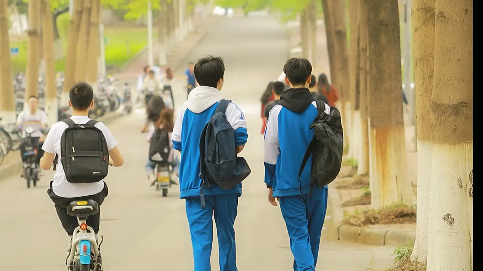 A high school entrance in Wuhan with students in uniform entering or exiting, showing the daily rhythm of the intense academic environment that defines parents' education obsession