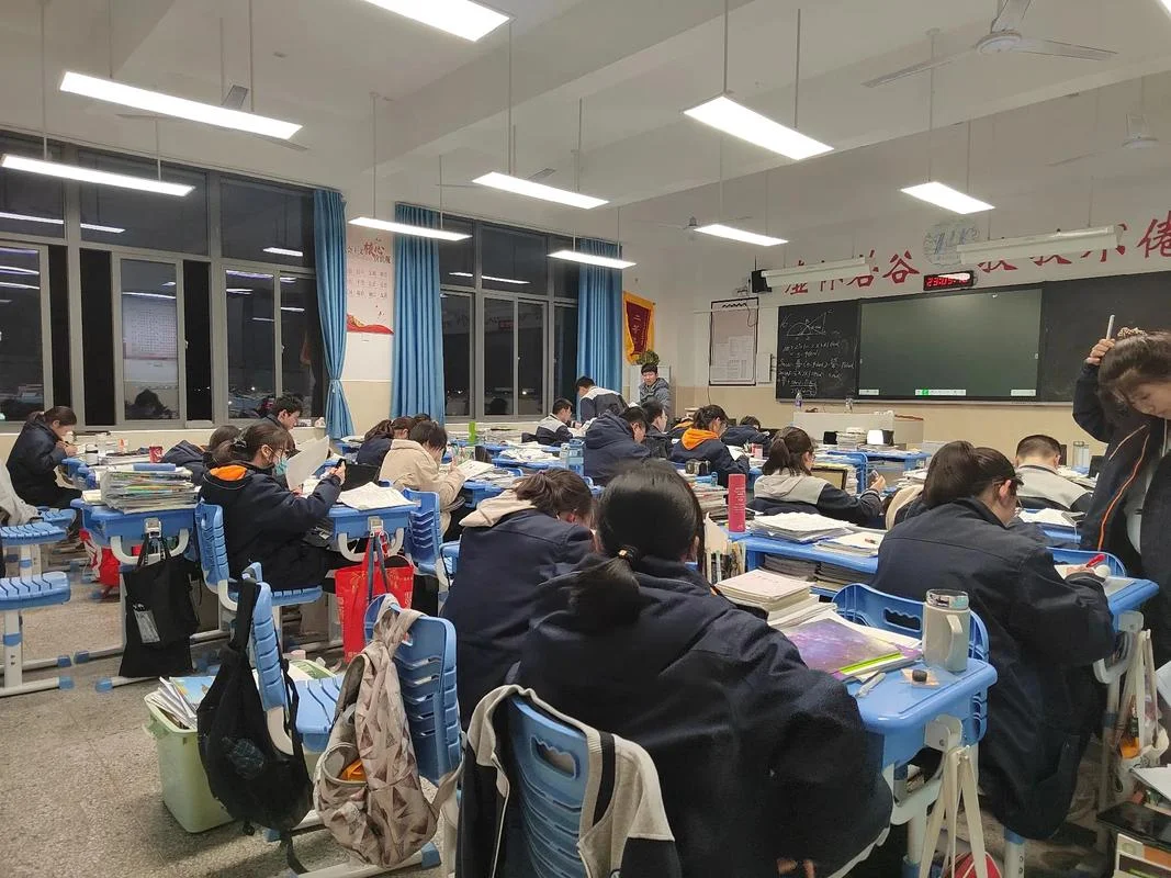 A close-up of gaokao preparation materials, test papers, or students studying late into the night at a Wuhan tutoring school or library, representing the immense academic pressure students face
