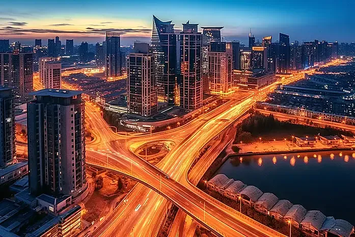 Wuhan elevated highway interchange at dusk, showing multiple levels of curving concrete ramps with car lights turning on in golden light