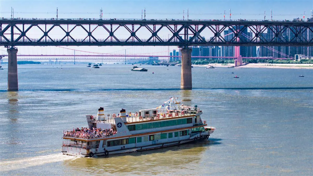 Wuhan ferry boat crossing the Yangtze River with city skyline visible on both banks at sunset
