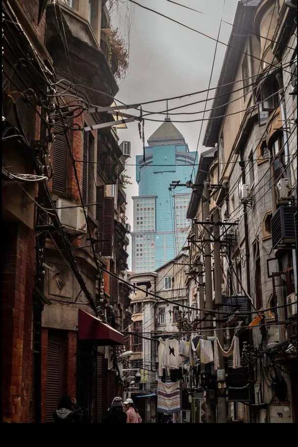 Inside a Hankou lifang alleyway with red brick walls, hanging laundry, bicycles, and an elderly resident sitting outside their door