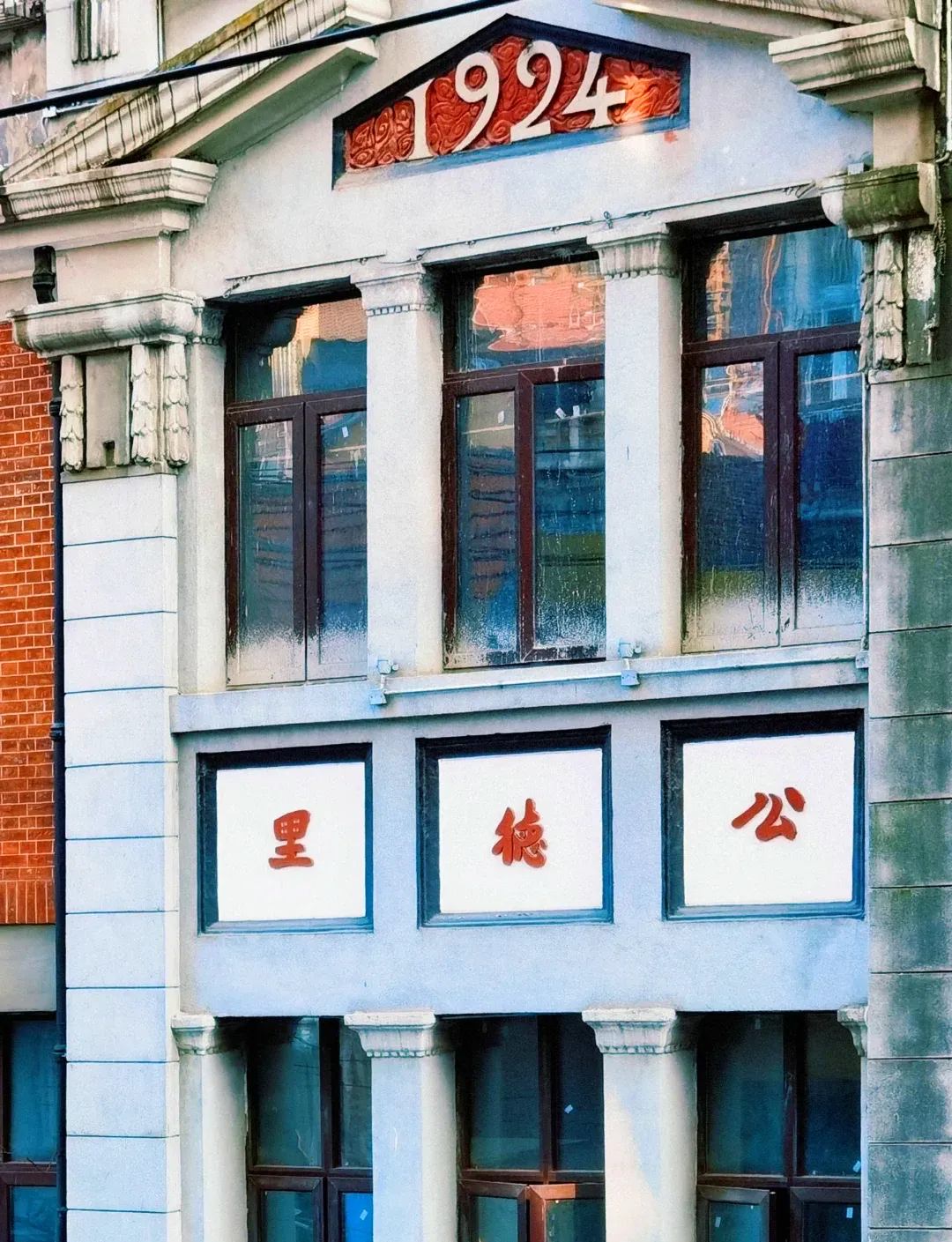 Entrance to a lifang alleyway in old Hankou, showing a brick gateway leading into a narrow corridor with laundry hanging between red-brick walls