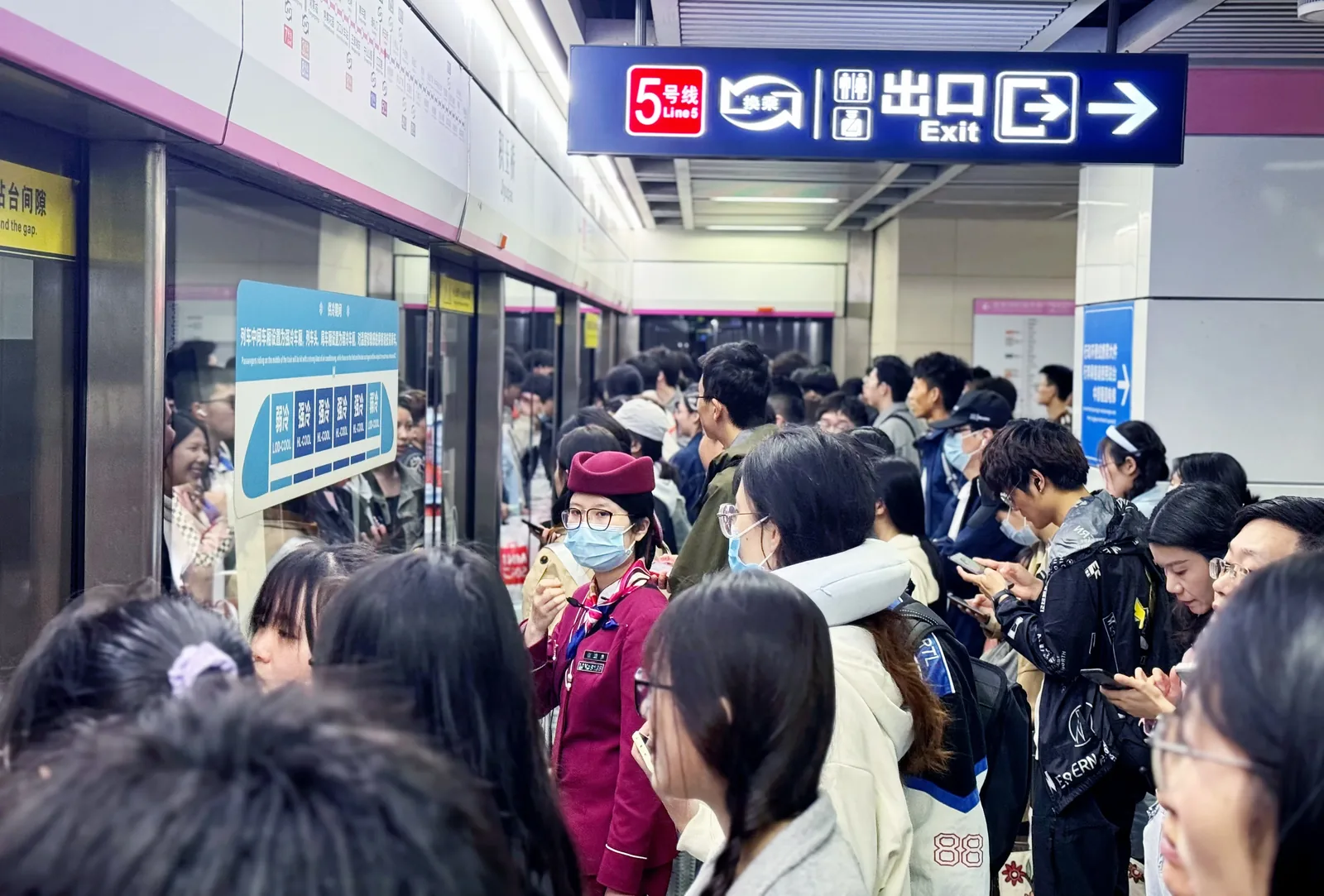 Busy Wuhan Metro platform with passengers waiting for an arriving train, modern station design with clear signage