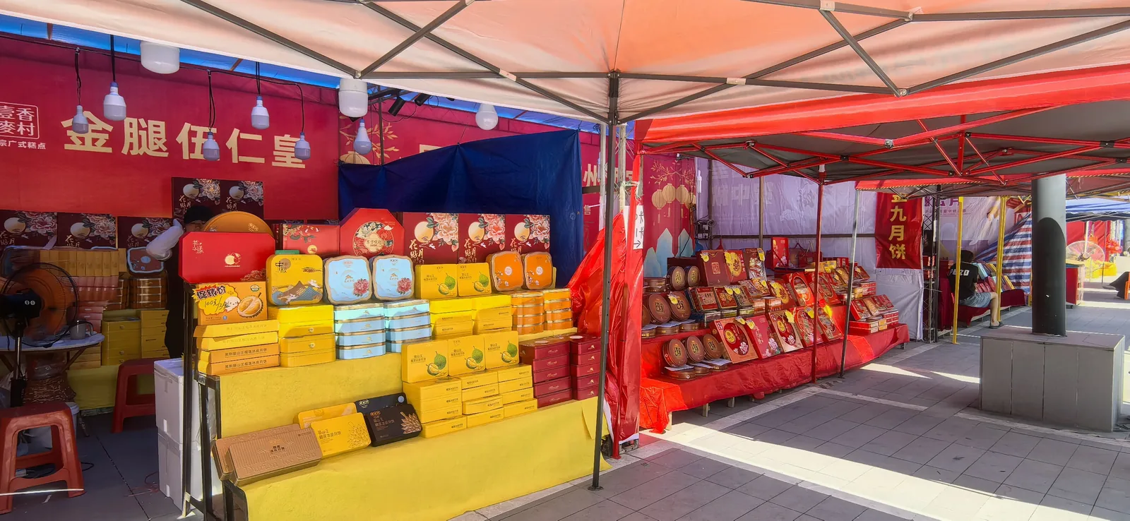Mid-Autumn Festival atmosphere in Wuhan with colorful mooncake boxes stacked at a market or shop, representing the gift-giving culture that defines the holiday