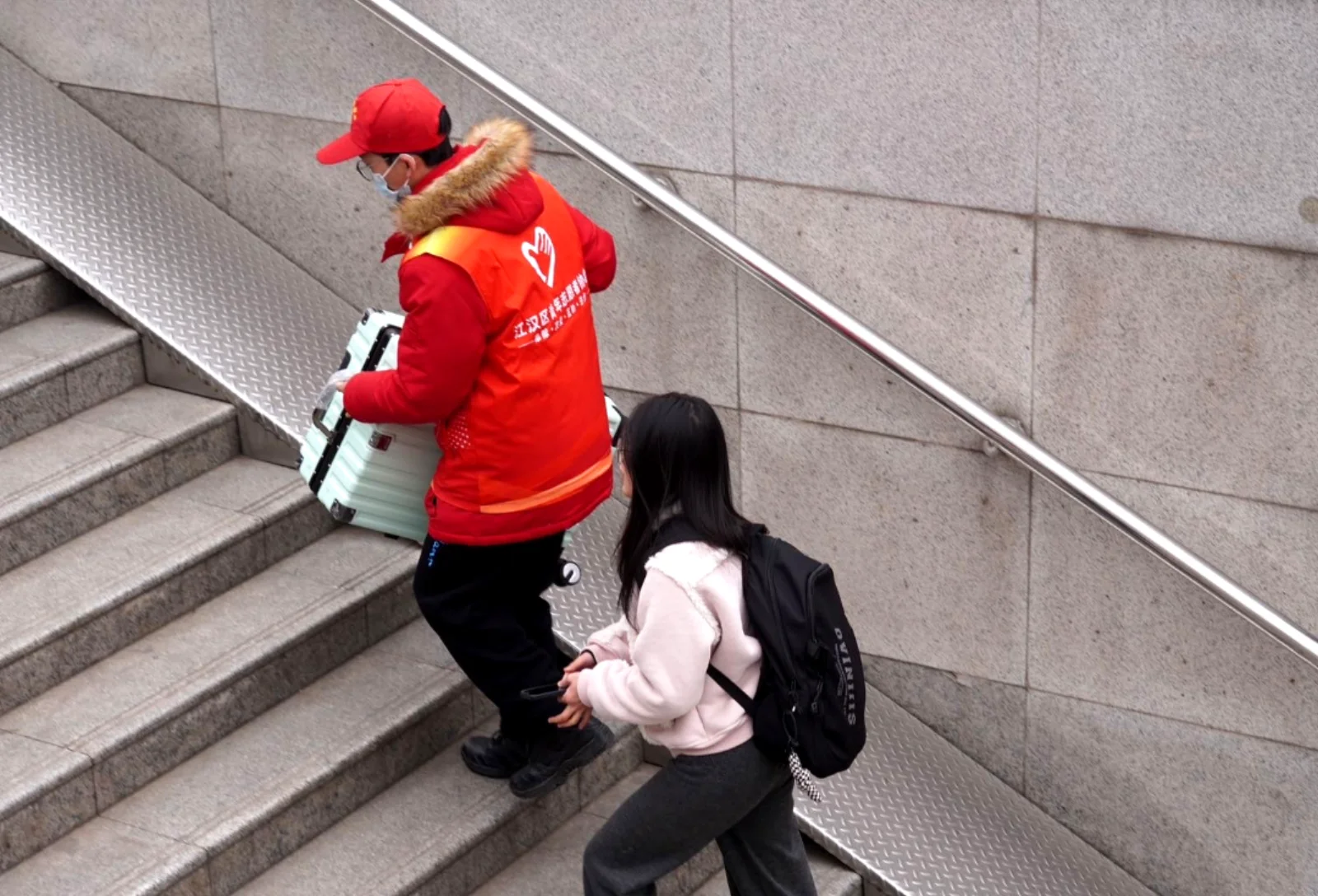 A Wuhan local quietly picking up a dropped bag and handing it back to a confused-looking foreign traveler on a busy sidewalk, already walking away before thanks can be offered
