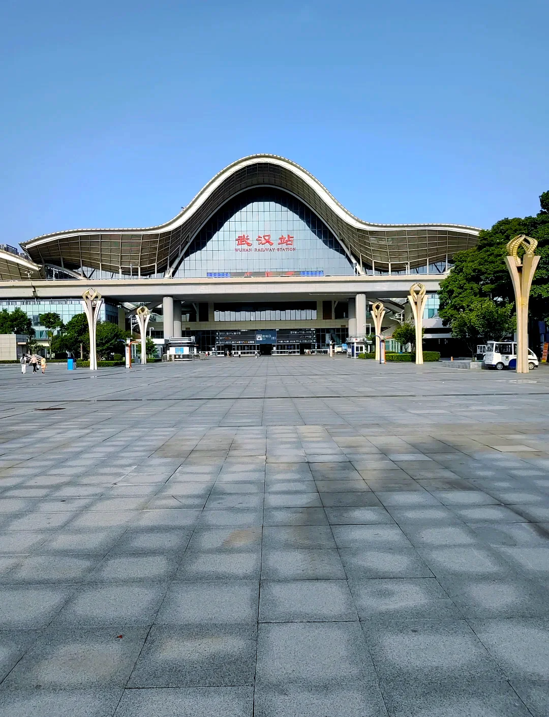 Wuhan high-speed rail station at Hankou or Wuchang, crowds of travelers pulling suitcases toward platforms bound for other provinces, capturing the powerful outbound energy of a city that serves as central China's transit hub