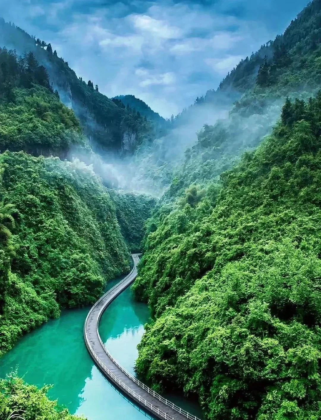 Dramatic natural scenery in Enshi or Zhangjiajie: a deep river canyon, towering rock formations, a long glass bridge spanning a gorge, representing Hubei's most dramatic natural landscapes that draw Wuhan weekend adventurers