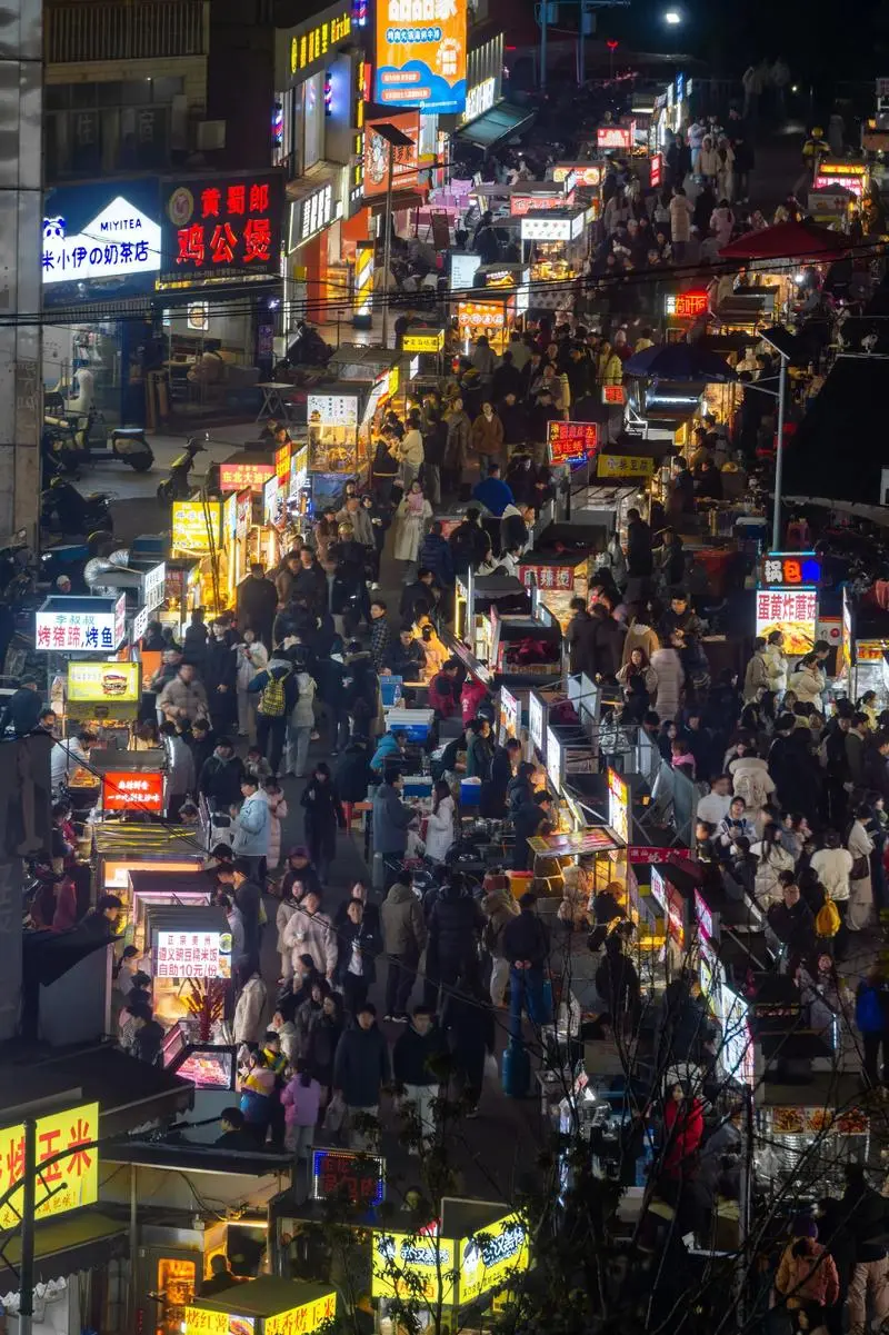 Street food stalls near Wuhan universities at night, with students eating barbecue and drinking beer at outdoor tables